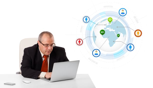 businessman sitting at desk and looking laptop with globe and social icons, isolated on white