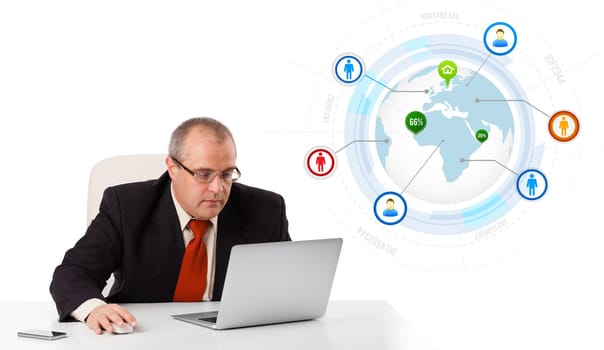 businessman sitting at desk and looking laptop with globe and social icons, isolated on white