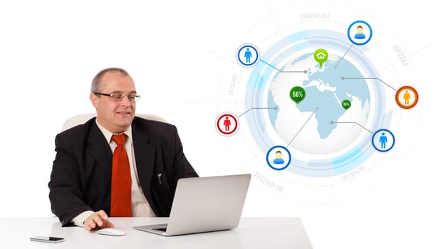 businessman sitting at desk and looking laptop with globe and social icons, isolated on white