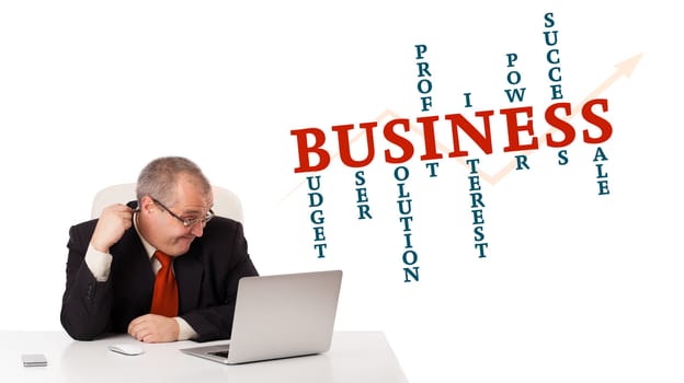 bisinessman sitting at desk and looking laptop with business word cloud, isolated on white