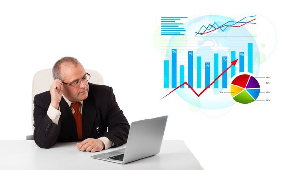 Businessman sitting at desk with laptop and statistics, isolated on white