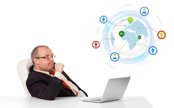 businessman sitting at desk and looking laptop with globe and social icons, isolated on white