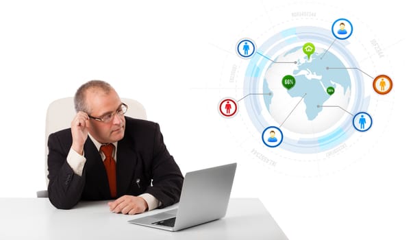 businessman sitting at desk and looking laptop with globe and social icons, isolated on white