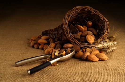 Assortment of nuts displayed in basket with nutcracker on hesian background