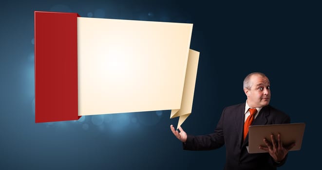 Businessman in suit holding a laptop and presenting modern origami copy space