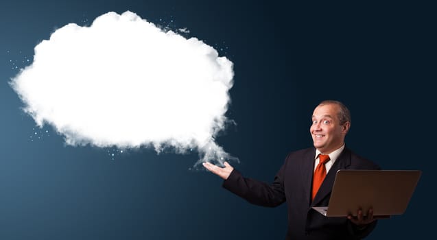 Businessman in suit holding a laptop and presenting abstract cloud copy space