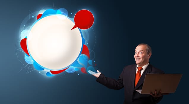 Businessman in suit holding a laptop and presenting abstract modern speech bubble with copy space