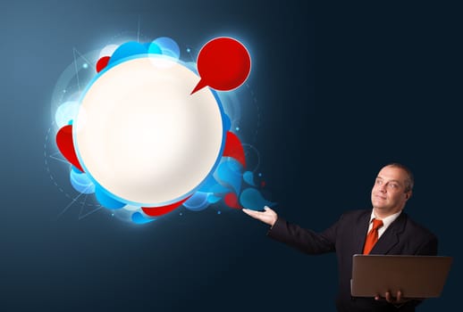 Businessman in suit holding a laptop and presenting abstract modern speech bubble with copy space