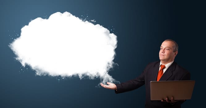 Businessman in suit holding a laptop and presenting abstract cloud copy space