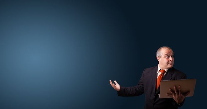businessman in suit holding a laptop and presenting copy space