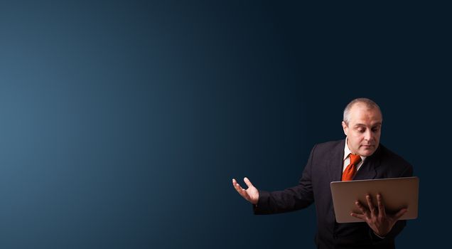 businessman in suit holding a laptop and presenting copy space