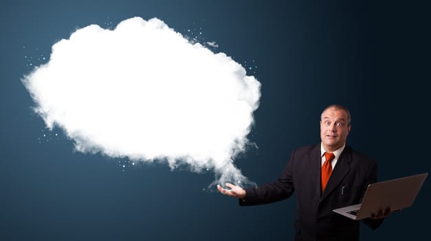 Businessman in suit holding a laptop and presenting abstract cloud copy space