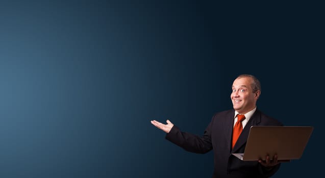 businessman in suit holding a laptop and presenting copy space