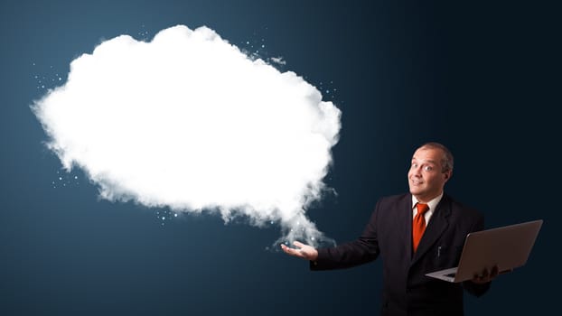 Businessman in suit holding a laptop and presenting abstract cloud copy space