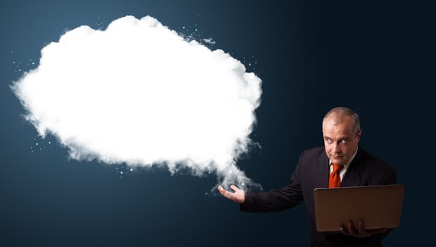 Businessman in suit holding a laptop and presenting abstract cloud copy space