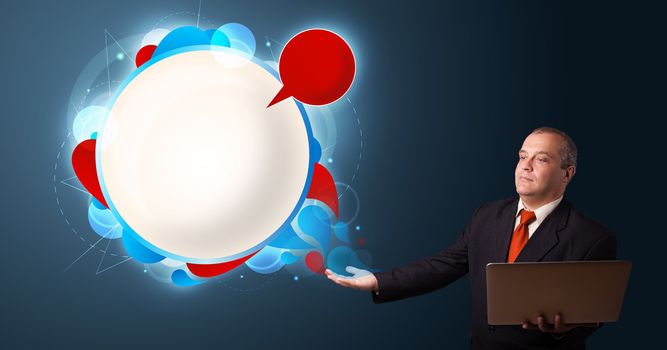 Businessman in suit holding a laptop and presenting abstract modern speech bubble with copy space