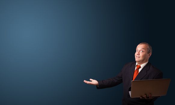 businessman in suit holding a laptop and presenting copy space