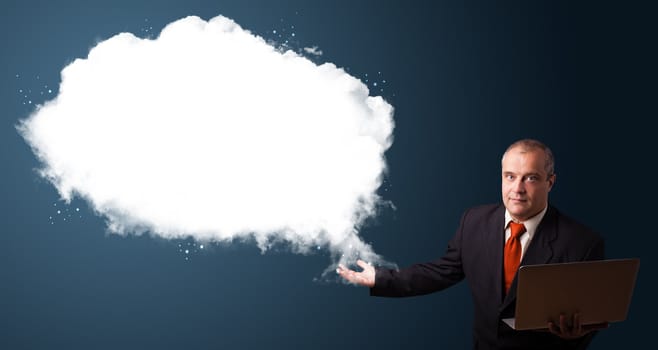 Businessman in suit holding a laptop and presenting abstract cloud copy space