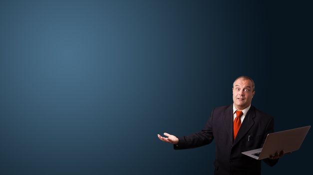 businessman in suit holding a laptop and presenting copy space