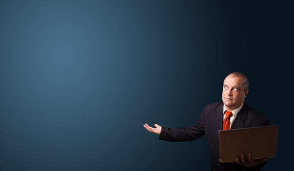 businessman in suit holding a laptop and presenting copy space