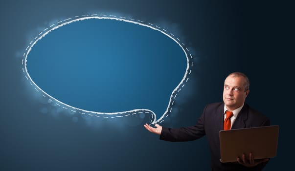 businessman in suit holding a laptop and presenting speech bubble copy space
