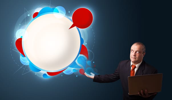 Businessman in suit holding a laptop and presenting abstract modern speech bubble with copy space