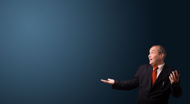 crazy businessman in suit holding a phone and presenting copy space
