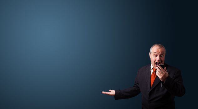 crazy businessman in suit holding a phone and presenting copy space