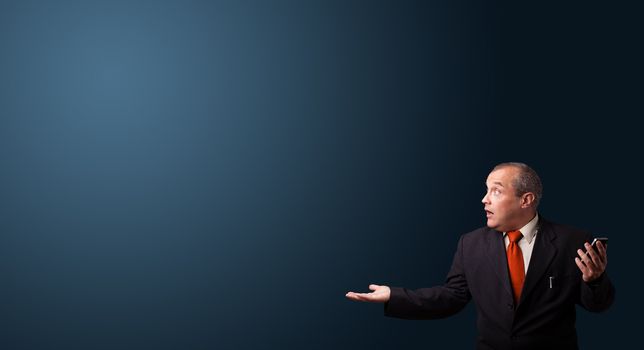 crazy businessman in suit holding a phone and presenting copy space