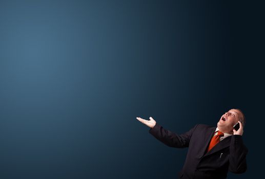crazy businessman in suit holding a phone and presenting copy space