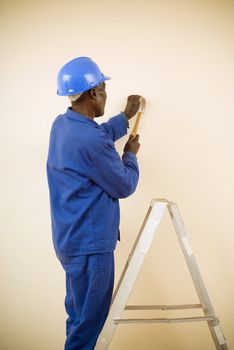 African American Construction Worker, Handyman, Carpenter, Standing on Ladder Working with Hammer