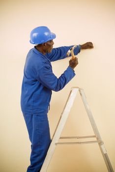 African American Construction Worker, Handyman, Carpenter, Standing on Ladder Working with Hammer