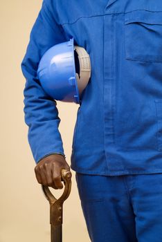 Close up of construction worker holding shovel and blue hard hat