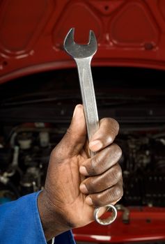 South African or American mechanic hand with spanner in front of car service engine maintenance