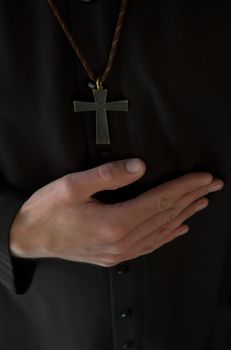Priest hand below crucifix on black robe