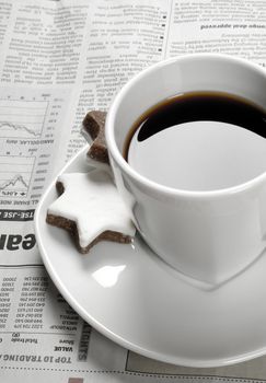 Cup of black coffee on financial newspaper and star shaped biscuits