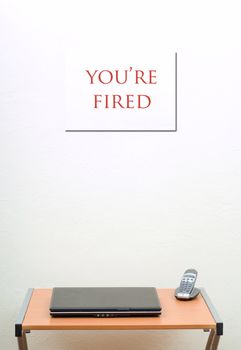 You're fired sign behind office desk with laptop and phone