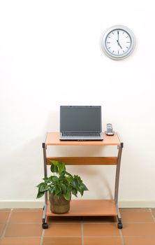 Office desk with laptop and phone, potplant under desk