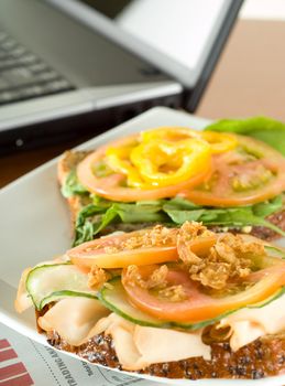 Office business lunch food open ham salad sandwich, laptop and financial newspaper on office desk