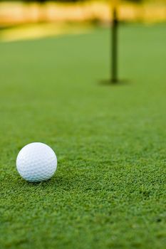 Golf ball on putting green next to hole