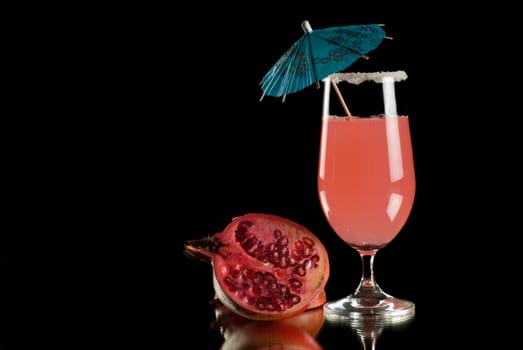 Brightly coloured cocktail drink with reflection and black background