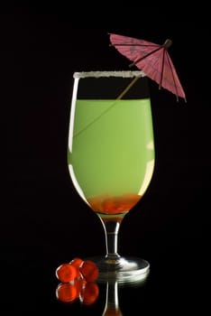 Brightly coloured cocktail drink with reflection and black background