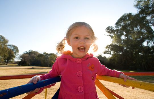 Happy young girl child play on roundabout in park