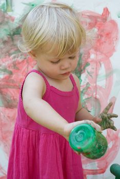 Baby little girl playing with paint artist