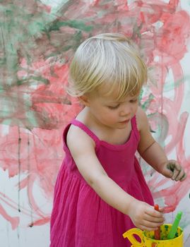 Baby little girl playing with paint artist