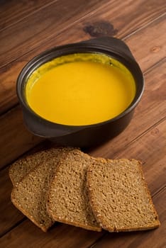Butternut soup and fresh home made bread on wooden table