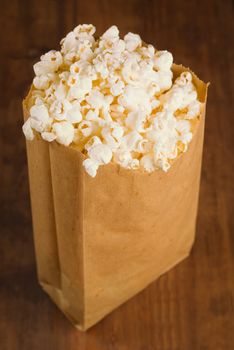 Bag of fresh popcorn on wooden kitchen table