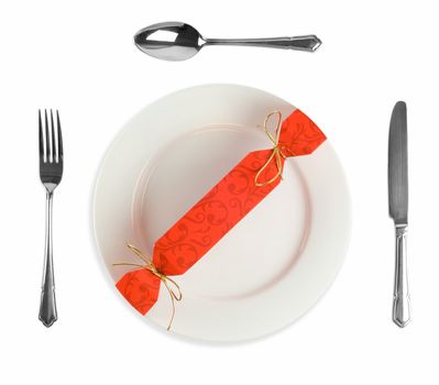 Christmas or party cracker on white dinner plate with knife, fork and spoon