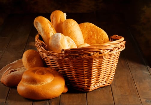 Basket of various fresh baked bread on wooden table
