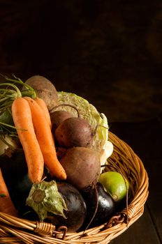 Thanksgiving basket filled with autumn fruits and vegetables on table with mottled background.